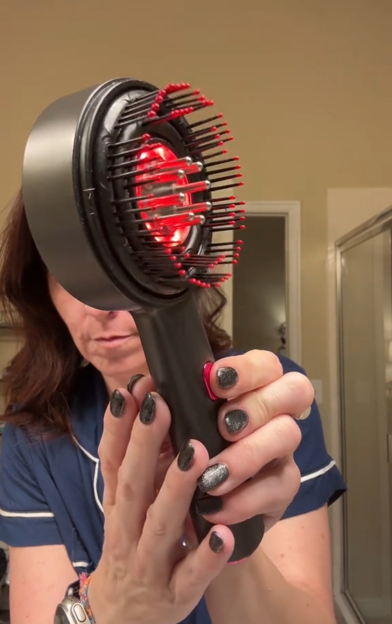 Person holding a hair styling tool with red interior in front of a mirror.